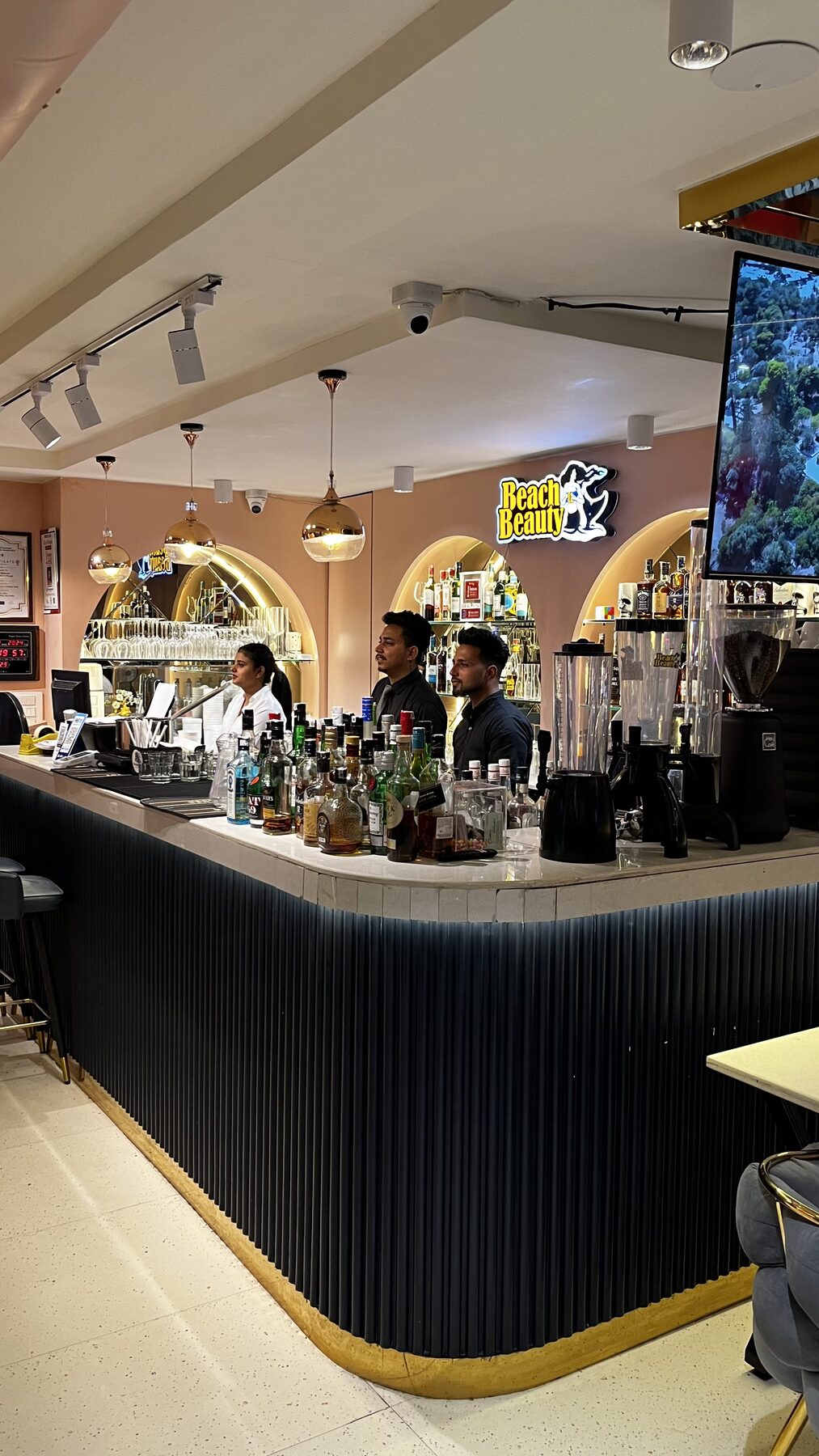 Bartenders behind the premium indoor bar counter with arched spirit shelves at The Bellrocc, Patiala