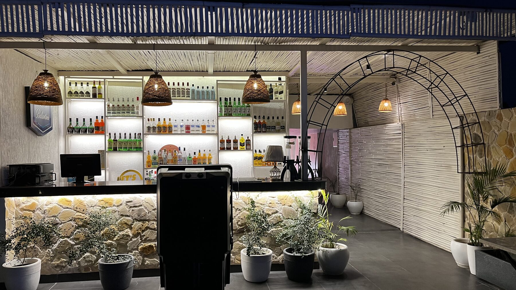 Stone-clad rooftop bar counter with backlit spirit shelves at The Bellrocc, Patiala